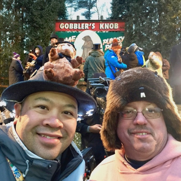 Two men wearing groundhog hats in front of Gobbler's Knob stage on Groundhog Day