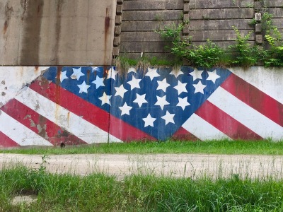 mural of American flag on retaining wall along bicycle trail