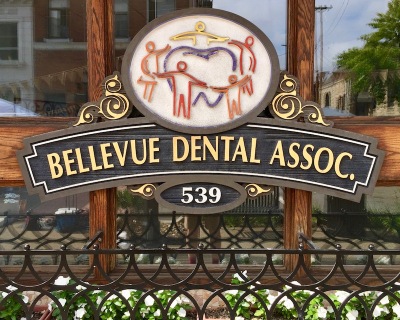 ornate sign for Bellevue Dental Associates with people forming ring around giant tooth