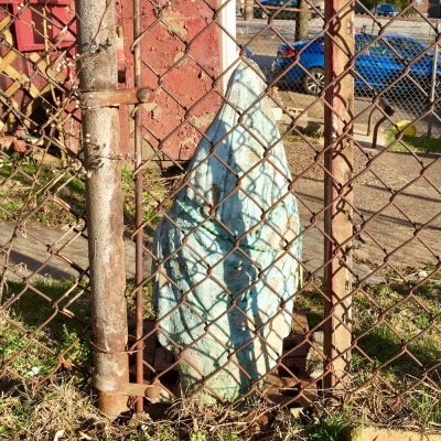 rear-view statue of Mary behind chain link fence