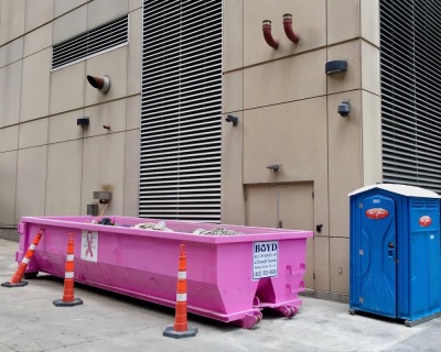 pink breast cancer awareness dumpster behind large building