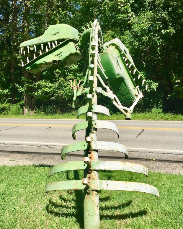 sculpture of dinosaur with two heads made from recycled auto parts