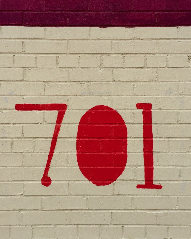 hand-painted address marker on brick wall