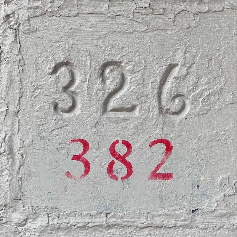 address marker with different house numbers carved into masonry and painted on