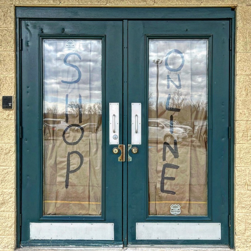 retail store glass front doors with large signs reading "Shop Online"