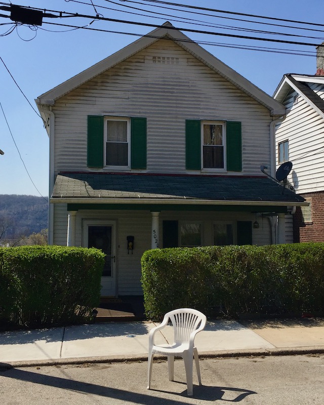 plastic lawn chair on street in front of small house