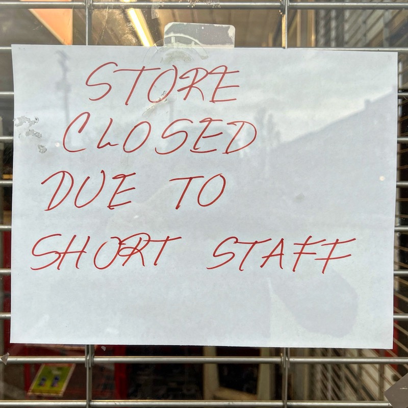 sign taped in store window with message "Store closed due to short staff"
