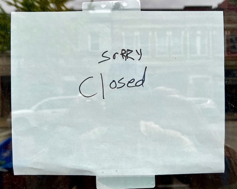 sign taped in store window with message "srrry closed"