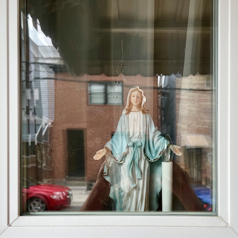 rowhouse window with statuette of Mary