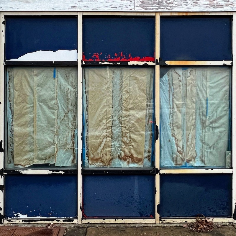 large retail windows covered with weathered paper