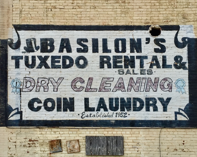hand-painted sign for tuxedo rental painted on brick wall