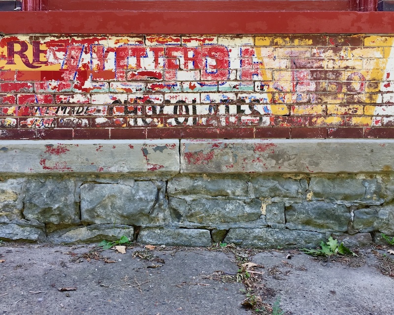 brick wall painted with many layers of faded advertisements