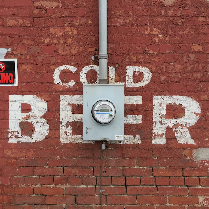 brick wall painted with faded advertisement for cold beer