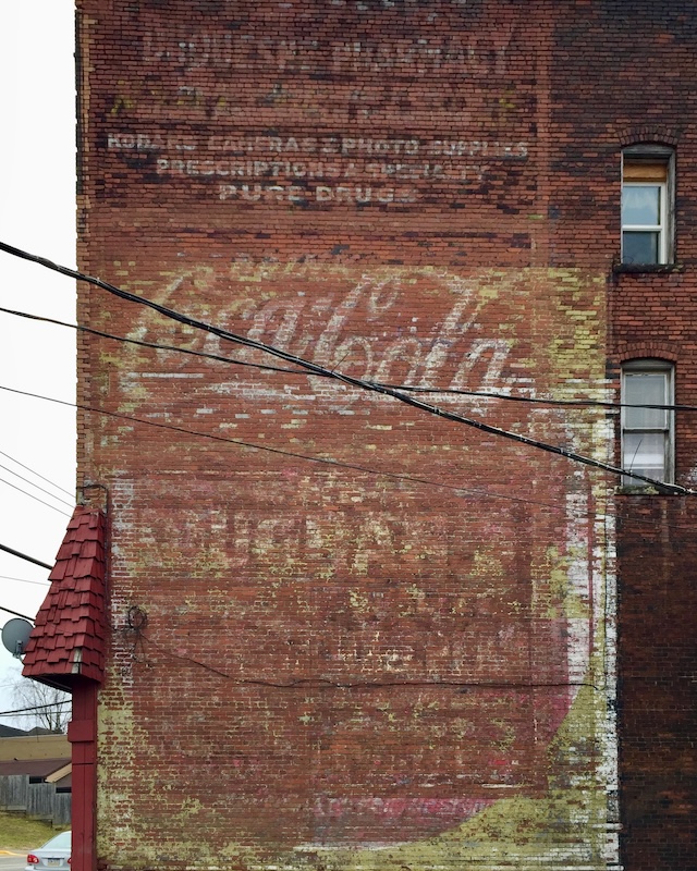 brick wall painted with faded advertisement for Coca-Cola