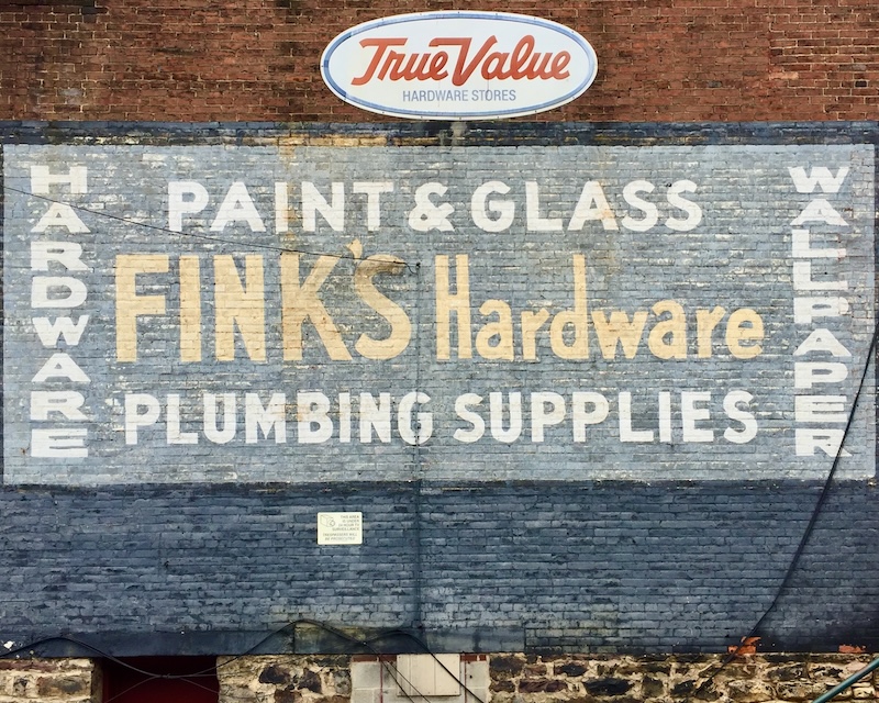 hand-painted sign for hardware store painted on brick wall