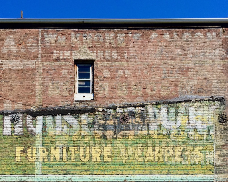 hand-painted sign for furniture store painted on brick wall