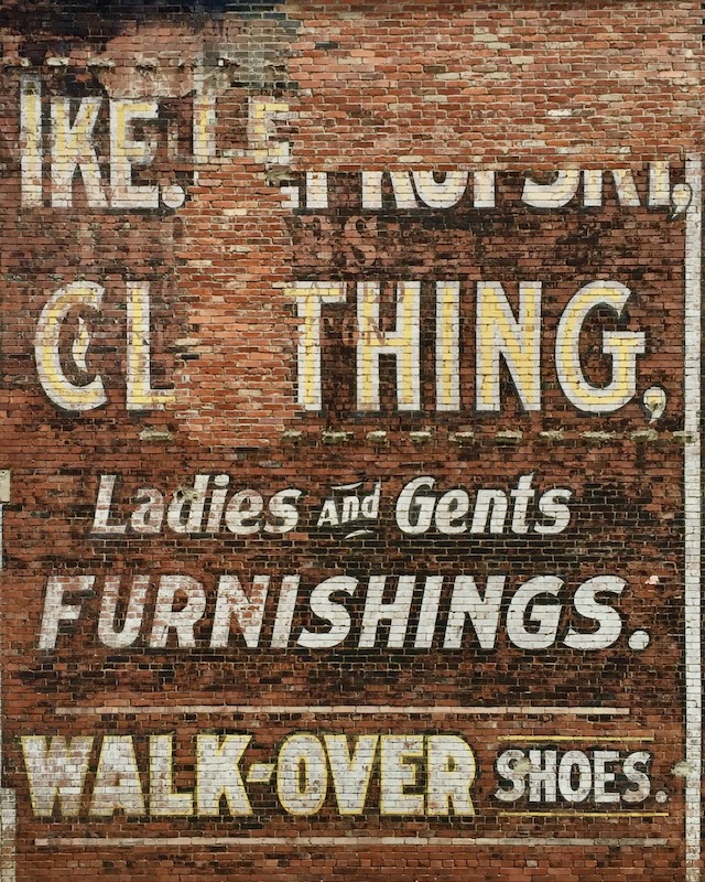 hand-painted sign for clothing store painted on brick wall