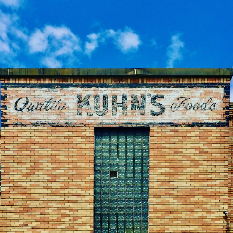 brick wall painted with faded advertisement for Kuhn's grocery store