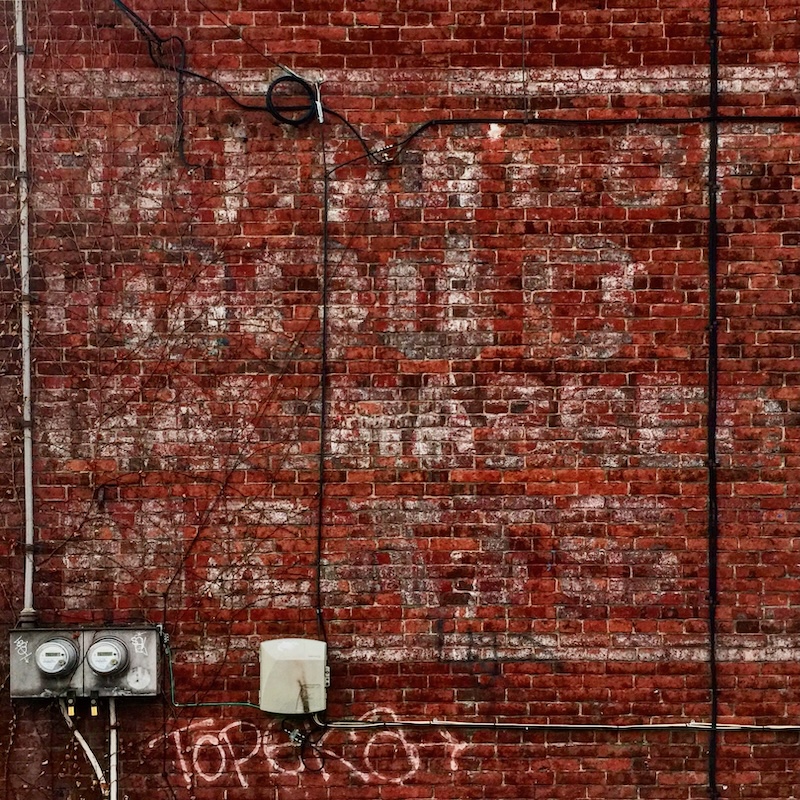 faded ghost sign for butcher painted on brick wall