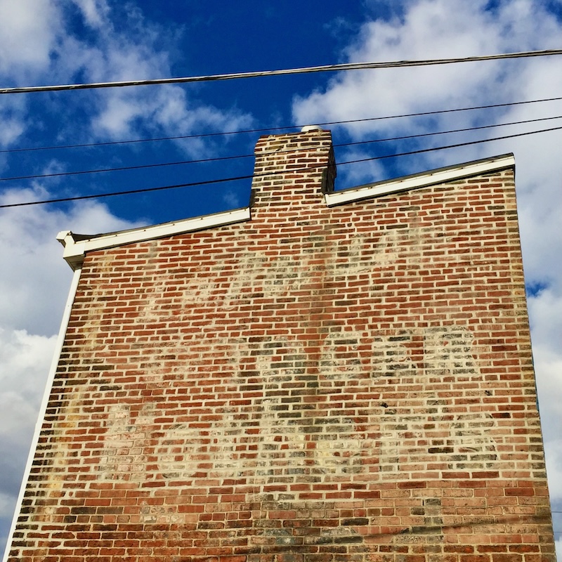 brick wall painted with faded advertisement for long-gone grocery store