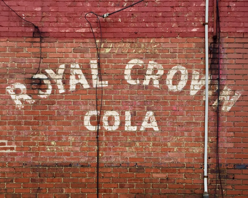 brick wall painted with faded advertisement for RC Cola