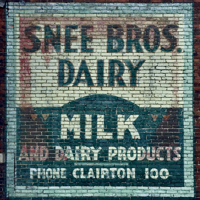 brick wall painted with faded advertisement for long-gone dairy