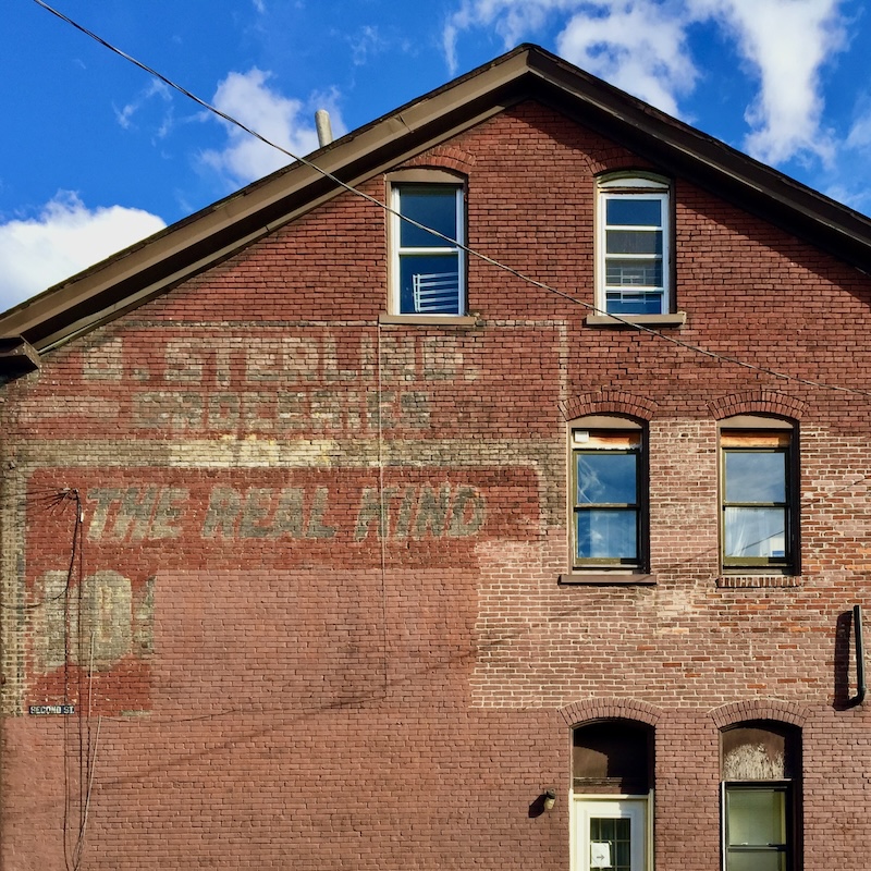 brick wall painted with faded advertisement for long-gone grocery store