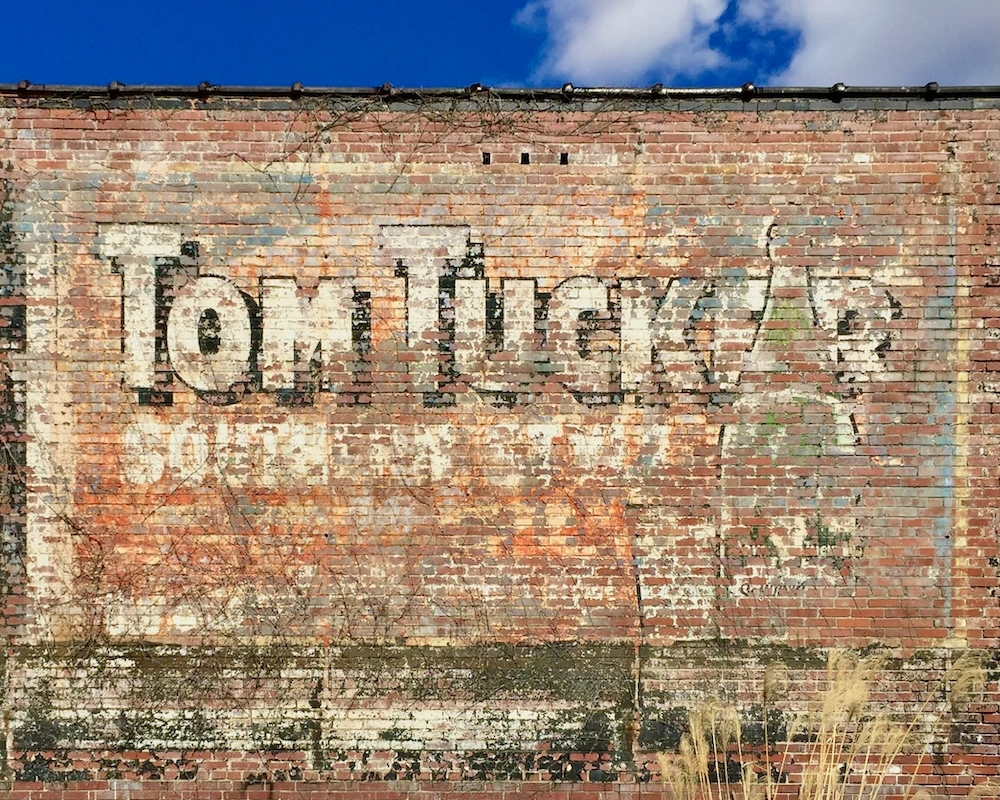 brick wall painted with faded advertisement for Tom Tucker ginger ale
