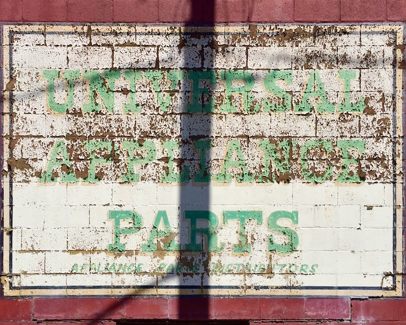 faded hand-painted sign for appliance parts store painted on brick wall