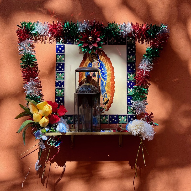 shrine to Virgin Mary of Guadalupe on bright-colored wall